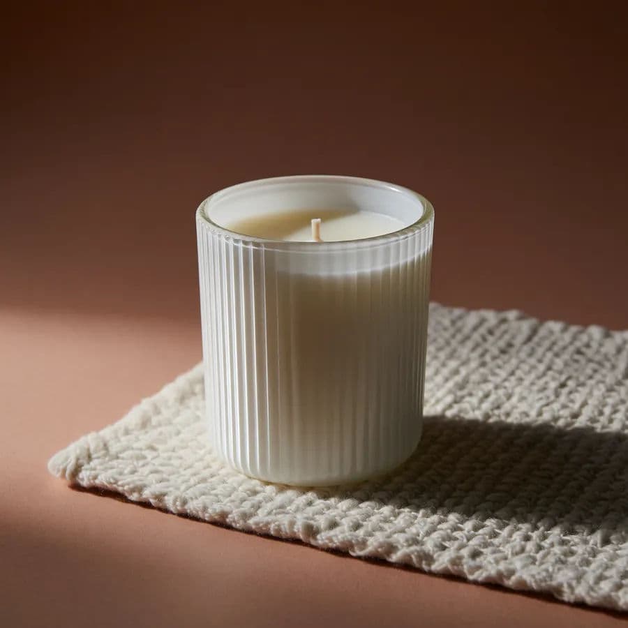 The same white ribbed jar candle in a warm styled lifestyle scene