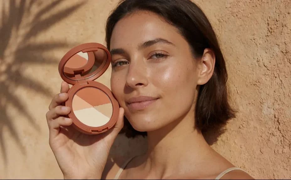 Cosmetics campaign direction with a model holding the product in warm sunlit styling