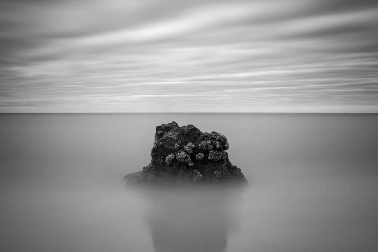 Long exposure black and white seascape with smooth water around a dark rock, generated with Krea 2 Medium