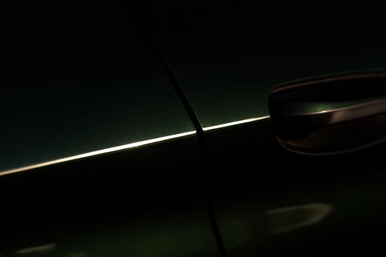 Photograph of the shut line and door handle of a dark car in very low raking sun, generated with Krea 2 Large