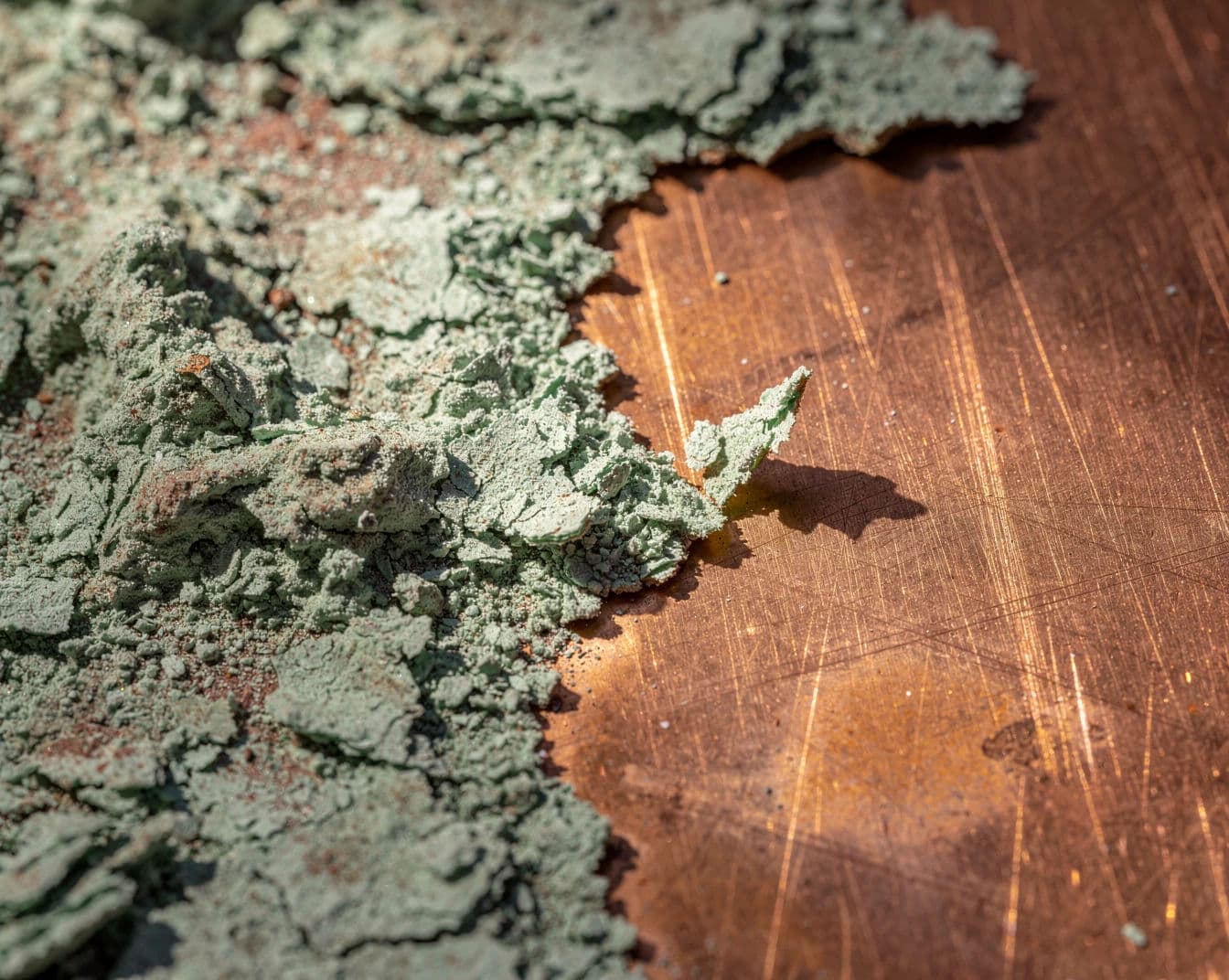 Macro photograph of green verdigris crusting across a copper surface in raking light, generated with Flux 2 Pro
