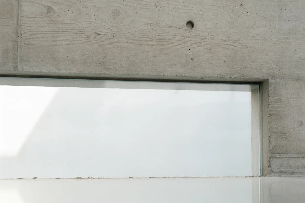 Photograph of a junction where a raw concrete wall meets a frameless pane of glass, generated with Krea 2 Medium