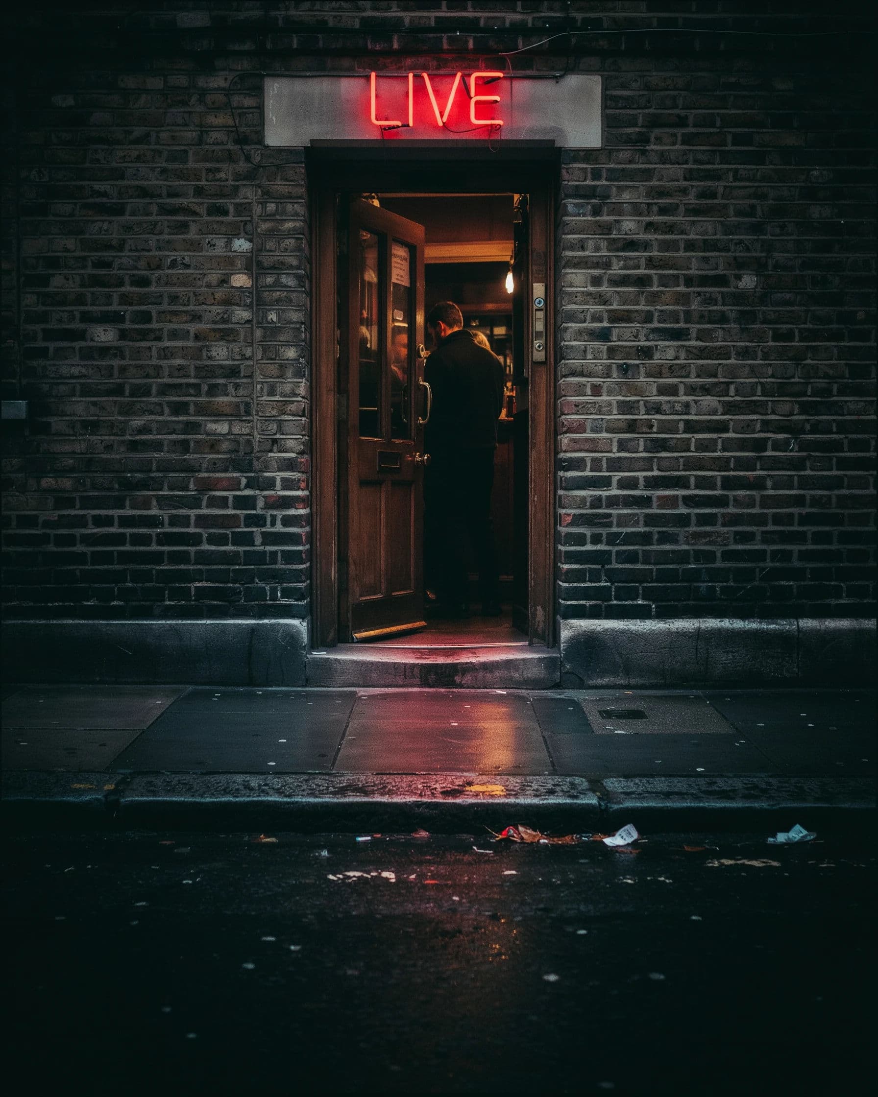 Photograph of a bar doorway with a LIVE sign throwing colour onto the wet kerb, generated with Ideogram 4.0