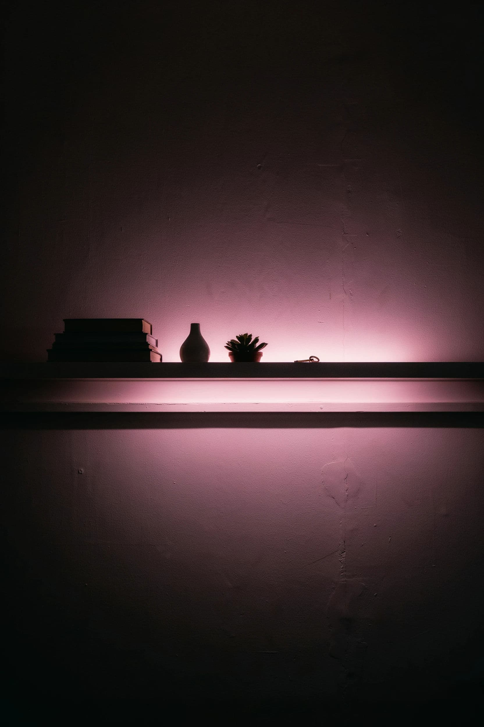 Vertical photograph of concealed neon tube glowing from behind a shelf in a dim room, generated with Ideogram 4.0