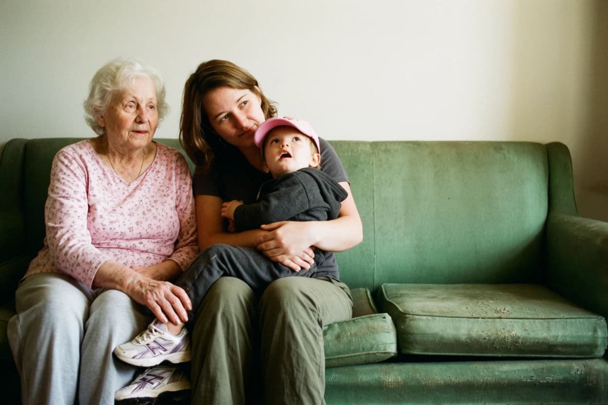 Portrait of a grandmother, mother and small child sitting together on a worn sofa in soft afternoon light, generated with Krea 2 Large