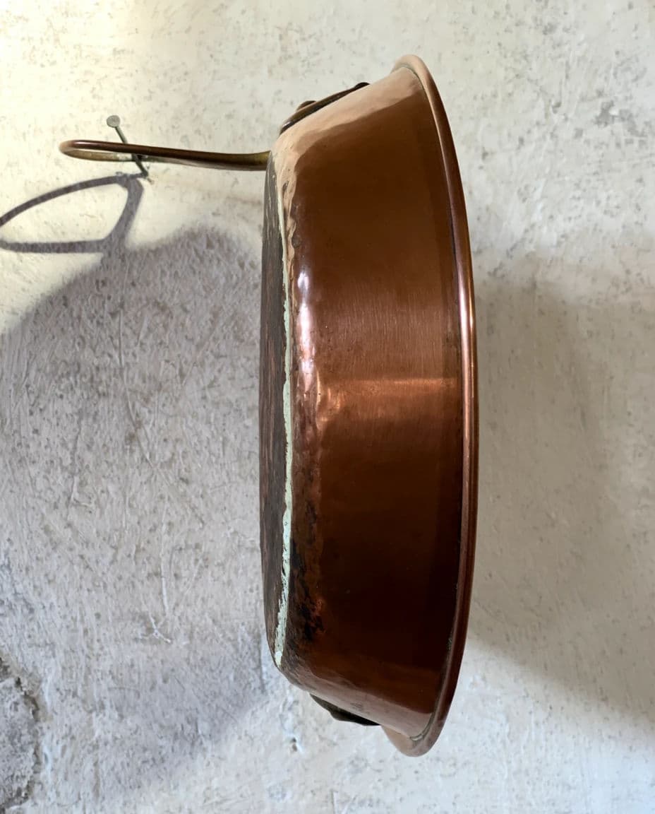 Still life of a single copper pan hanging on a nail against a rough plaster wall, generated with Krea 2 Large