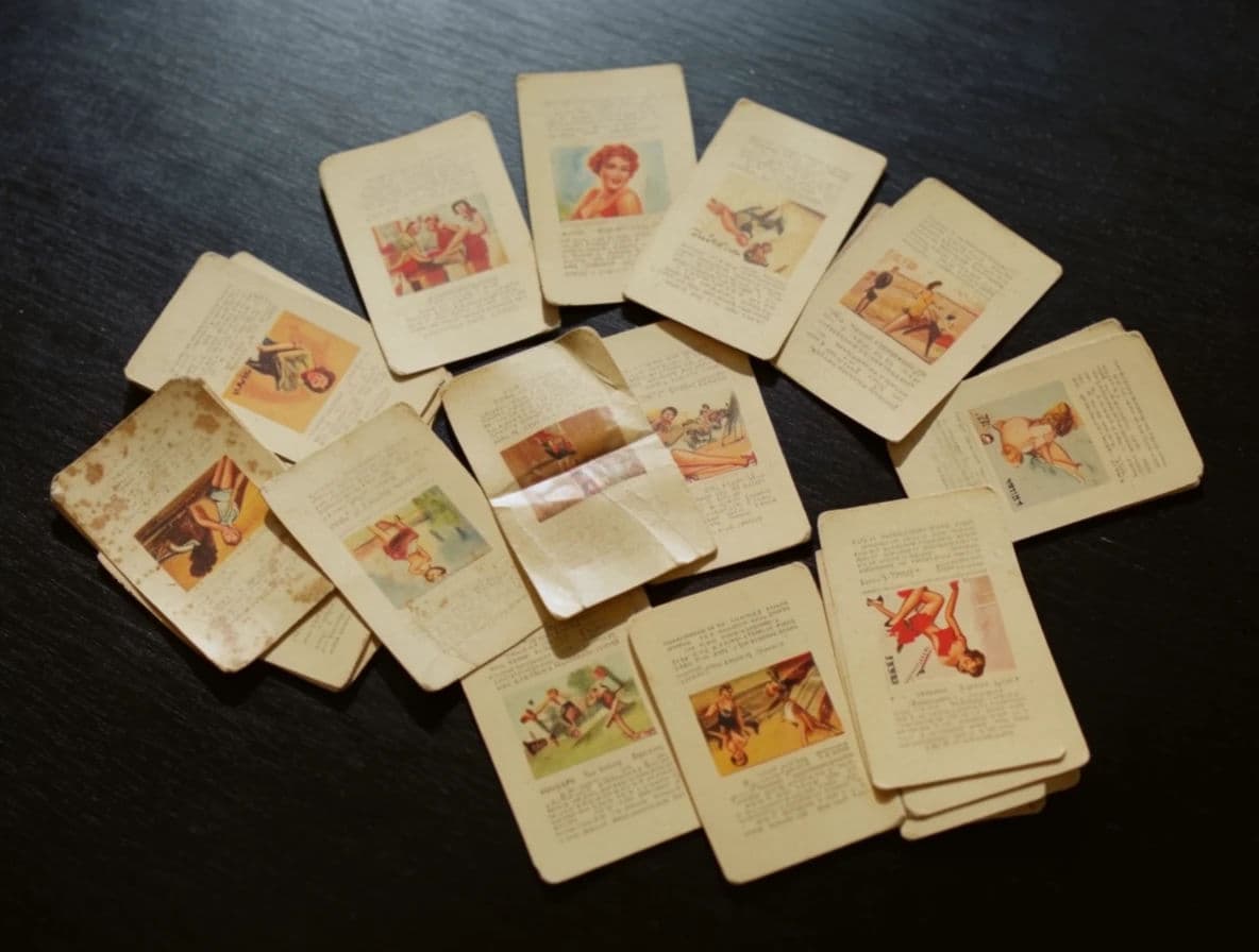 Still life of old collectable cards fanned across a dark table with worn corners, generated with Krea 2 Large