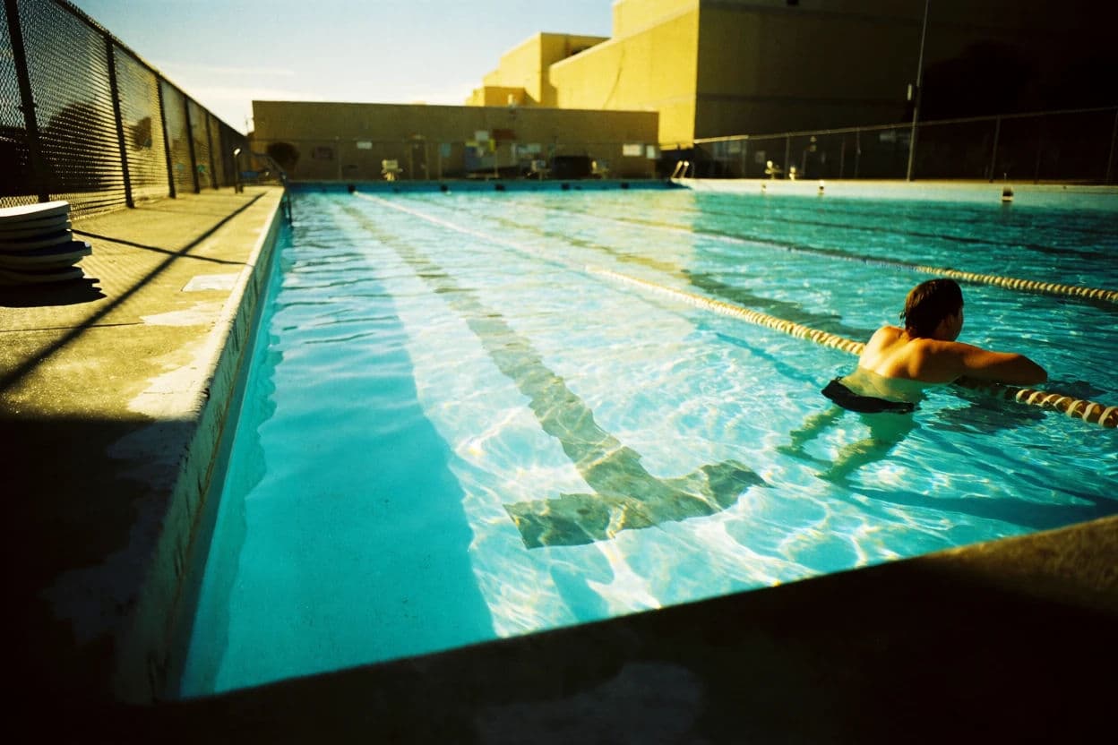 Cross-processed photograph of a public swimming pool with cyan shadows and blown highlights, generated with Krea