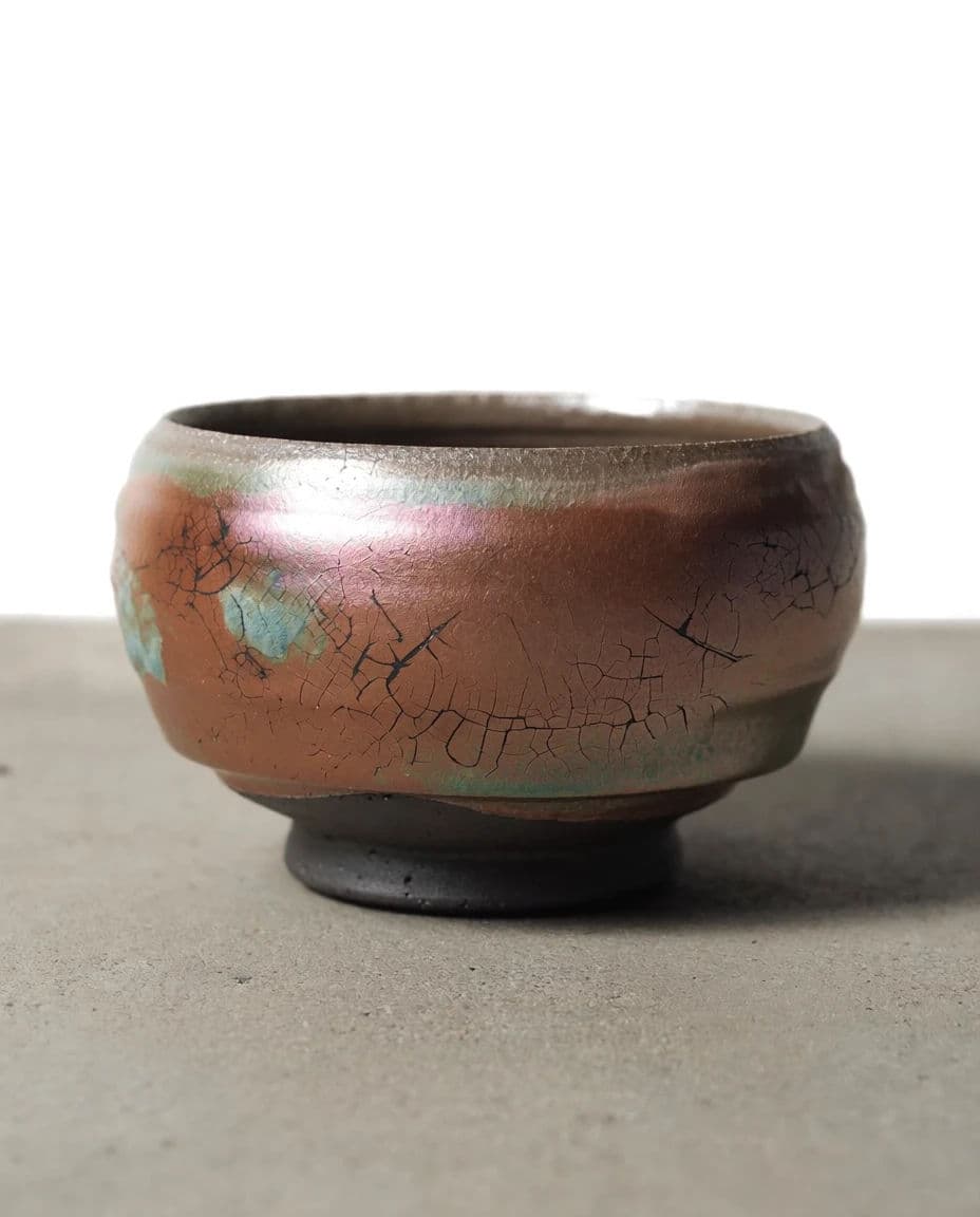 Raku fired ceramic bowl with crackle glaze and metallic flash, generated with Krea